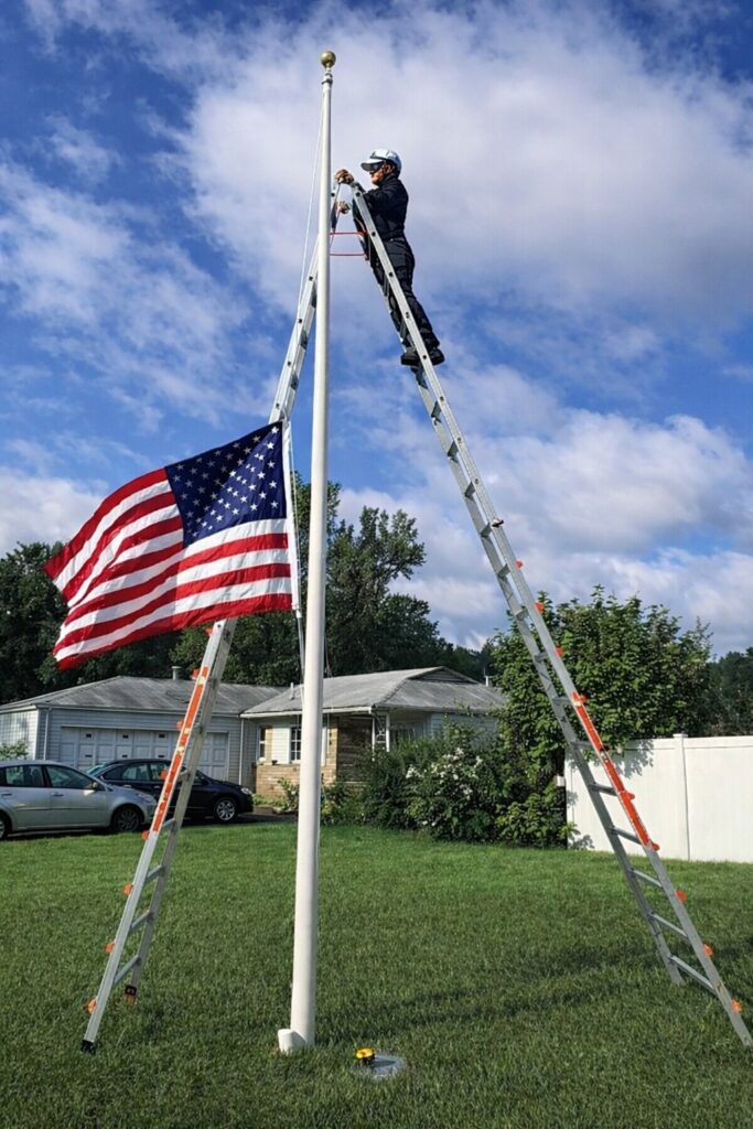 Professional flagpole repair service performed by a technician on a ladder Flagpole Repair Service